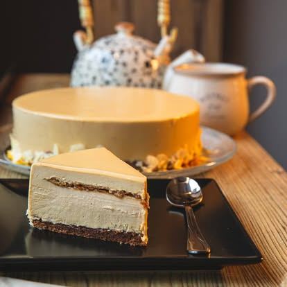 Tort mousse cu glazură de caramel și felie pe farfurie neagră