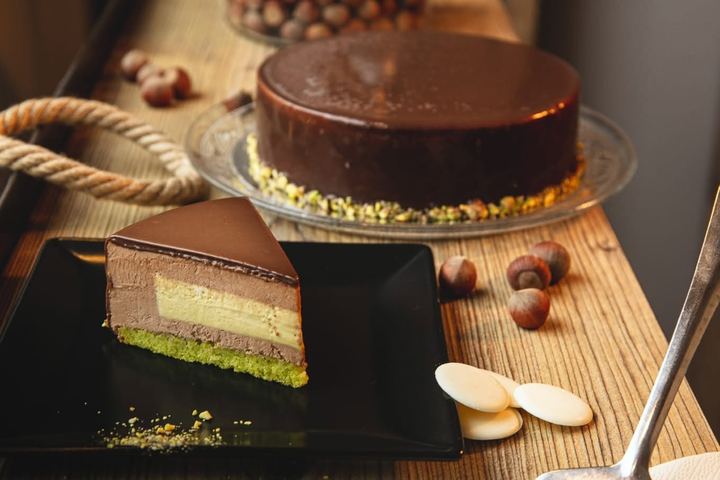 Tort cu glazură de ciocolată și blat de fistic, cu alune de pădure